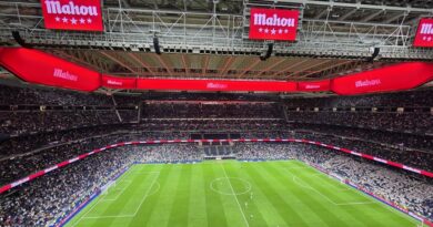 An empty football stadium with red advertising banners, evoking a transfer window contract standoff