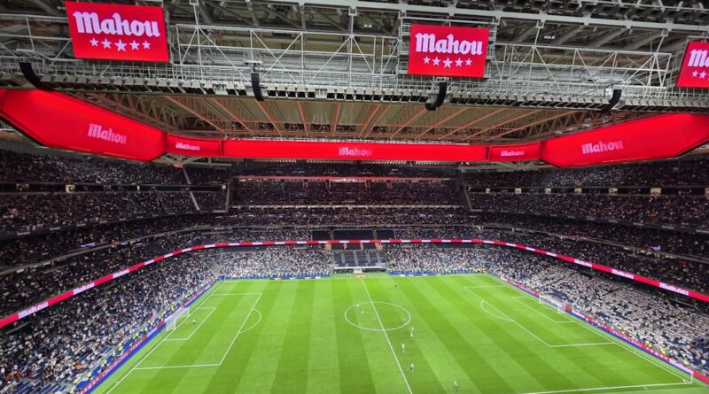 An empty football stadium with red advertising banners, evoking a transfer window contract standoff