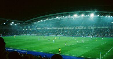 A football match under floodlights in a packed stadium at night