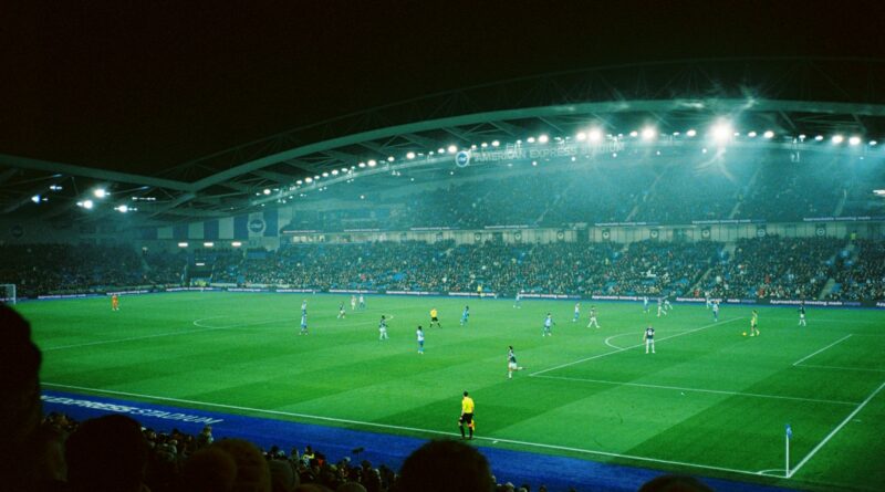 A football match under floodlights in a packed stadium at night